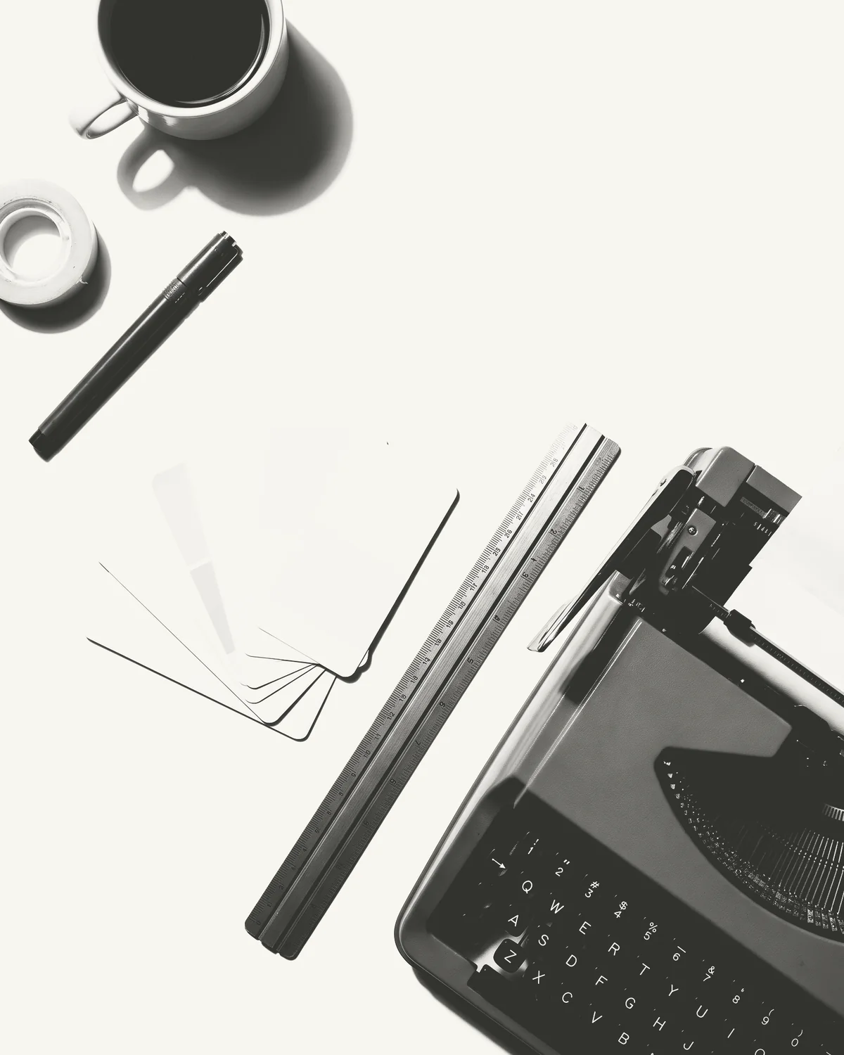 Escritorio visto desde arriba: máquina de escribir, regla, taza de café, cartas de color y un marcador